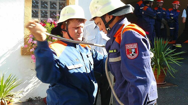 Roland Schneider beim Anlegen des Brustbundes bei seinem Teamkollegen Michael Rohleder.