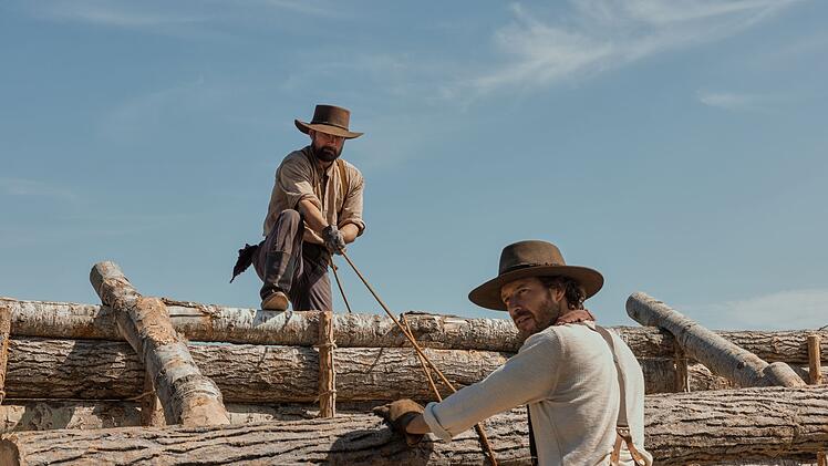 Das "Little House on the Prairie" (Auf Deutsch: "Das kleine Haus in der Pr&auml;rie") baut sich nicht von alleine. Charles Ingalls (Luke Bracey, rechts) bekommt dabei Hilfe von John Edwards (Warren Christie). Er wurde den Ingalls' auch in der ersten Serienadaption ein guter Freund. Er ist in Laura Ingalls Wilders B&uuml;chern sehr locker an eine wahre Person angelehnt.