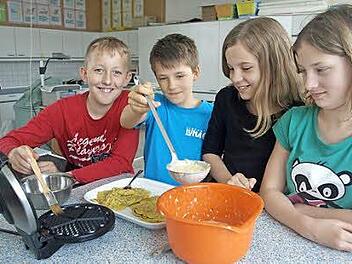 Marcel (von links) bestreicht das Waffeleisen mit Öl, ehe Bastian den Teig einfüllt. Antonia und Charlotte passen auf, dass alles richtig läuft und die Waffeln gut werden. Foto: Stefan Geiger