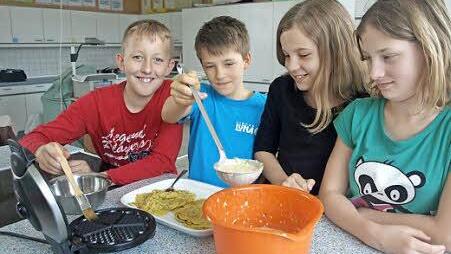 Marcel (von links) bestreicht das Waffeleisen mit Öl, ehe Bastian den Teig einfüllt. Antonia und Charlotte passen auf, dass alles richtig läuft und die Waffeln gut werden. Foto: Stefan Geiger