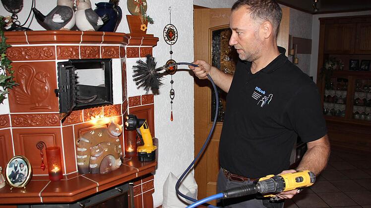 Markus Dütsch mit dem elektrobetriebenen flexiblen Kehrbesen am Kachelofen Foto: Friedwald Schedel