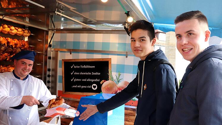 Das Hähnchenauto am Marktplatz in Adelsdorf: Eugen Nicolae Birlonca grillt für Gabriel und Alexander Münch (von links).  Foto: Johanna Blum
