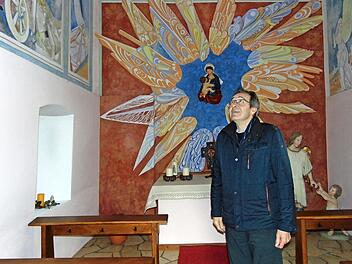 Pfarrer Josef Pingold betrachtet die Wandmalereien in der Marienkapelle. Foto: Petra Malbrich