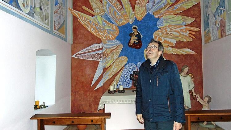 Pfarrer Josef Pingold betrachtet die Wandmalereien in der Marienkapelle. Foto: Petra Malbrich