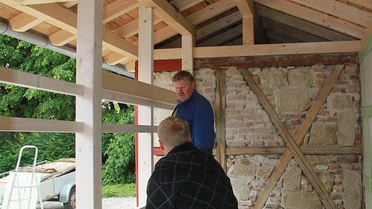 Die Handwerker Karl-Heinz und Christopher Geldner aus Nedensdorf bereiten an den Hölzern der Front des Bienenhauses den Einsatz der Fenster vor. Foto: Ramona Popp