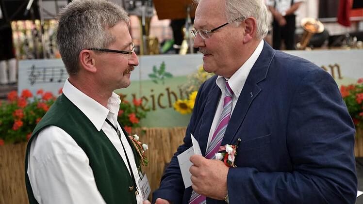 Schirmherr Claus Bittenbrünn war nicht ohne Geschenk, das er an den 1. Vorsitzenden der Blaskapelle Norbert Döll (links) übergab