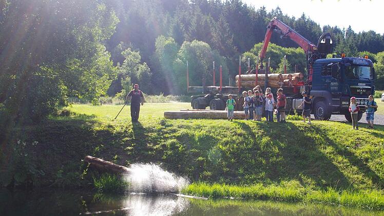 Josef Pfadenhauer und die Kinder beförderten die Baumstämme ins Wasser. Foto: Heike Schülein