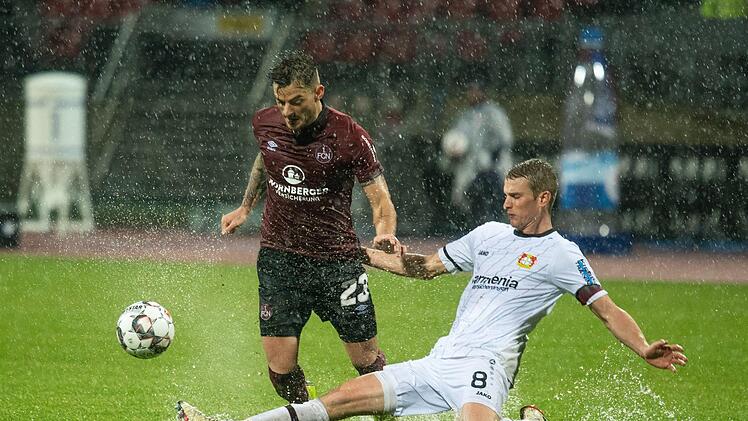 Das Hinspiel war eine richtige Wasserschlacht. In dieser Szene kämpfen Nürnbergs Tim Leibold (links) und Lars Bender um den Ball. Die Partie am 13. Spieltag endete 1:1. Foto: Nicolas Armer/dpa
