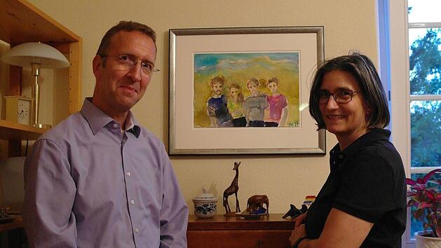 Stefano und Isolde Pettinella am Sekret&auml;r von seinem Urgro&szlig;vater und vor dem Bild ihrer vier Kinder. In ihrem Leben vereint sich viel: Alt und Neu sowie Erfahrungen aus vielen L&auml;ndern. Mit dem ganzen Wissensschatz haben sie sich nun dauerhaft f&uuml;r Bad Br&uuml;ckenau entschieden. Foto: Stefanie Elm