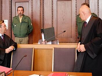 Der Angeklagte verbirgt sein Gesicht hinter einem Aktenordner. Foto: Nikolas Pelke