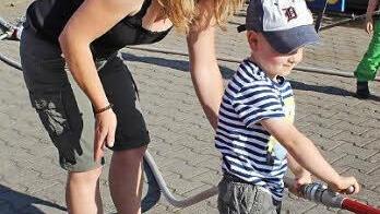 Voll aufdrehen und gut zielen. Da ist es praktisch, wenn die Mama ein bisschen mit hält, damit es den kleinen Feuerwehranwärter nicht gleich umhaut durch die Kraft des Wassers.
