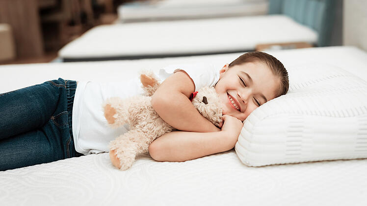 3334178 Smiling little girl lies on n orthopedic mattress in a f