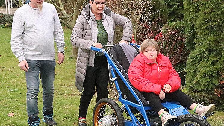 Geländegängig, leicht zu bedienen und steuerbar, elektrisch angetrieben ist der von Peter Sasse (links) konstruierte "Aktiv-Schiebe-Wagen" mit dem Ute Sasse die gemeinsame 22-jährige Tochter Luca ohne größeren Kraftaufwand transportieren kann.  Helmut Will