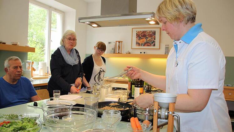 Kochkunst in der Lehrküche: Diätassistentin Barbara Jopp zeigt, wie sich Vollwertkost mit einfachen Mitteln zubereiten lässt. Die Patienten schauen ihr über die Schulter. Foto: Ulrike Müller