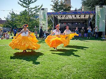Mexikanische Tänzerinnen in bunten, gelben Kleidern performen beim Welterbefest in Bamberg. Im Hintergrund sitzen Zuschauer und eine Bühne ist zu sehen.