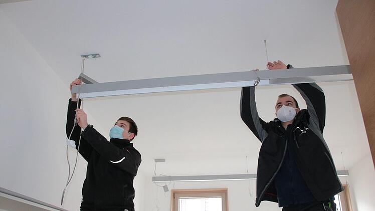 Dominik Fella (von links) und Luca Franke von der Euerdorfer Firma Elektro Schneider erledigen Restarbeiten in den Büros. Foto: Ralf Ruppert