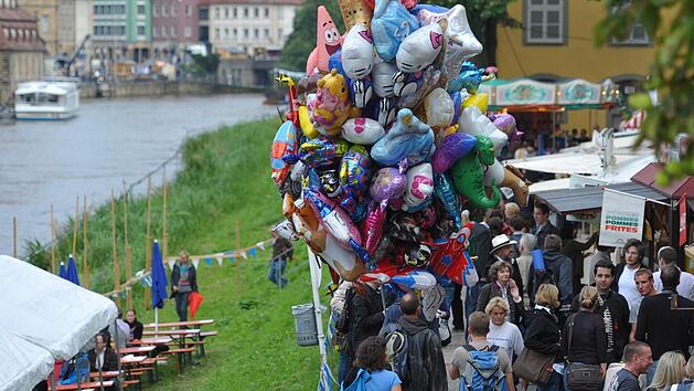 Ein H&auml;ndler mit bunten Luftballons geht am 18.08.2010 am Regnitzufer von Bamberg &uuml;ber die Sandkerwa. Foto: David-Wolfgang Ebener/dpa