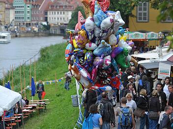Ein Händler mit bunten Luftballons geht am 18.08.2010 am Regnitzufer von Bamberg über die Sandkerwa. Foto: David-Wolfgang Ebener/dpa