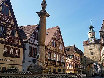 Malerische Fachwerkhäuser in einer fränkischen Stadt, von einem Reiseportal als eine der schönsten Deutschlands gekürt. Ein Brunnen und ein historischer Turm sind im Hintergrund sichtbar.