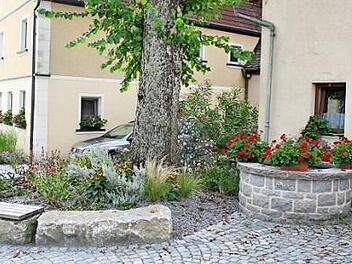 Der alte Brunnen von Warmersdorf (rechts im Bild) soll reaktiviert werden. Das Wasser soll zum Gießen der neuen Grünanlagen entnommen werden. Foto: Evi Seeger