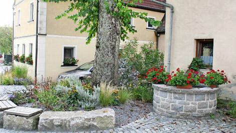 Der alte Brunnen von Warmersdorf (rechts im Bild) soll reaktiviert werden. Das Wasser soll zum Gießen der neuen Grünanlagen entnommen werden. Foto: Evi Seeger