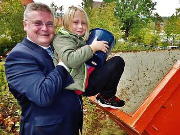 "Da komm ich mit meinem Apfeleimer ja nicht ran", stellt der kleine Marlon fest. Bankvorstand Thomas Siebenaller hilft deshalb ein wenig nach. Foto: Bernd Kleinert