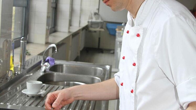 Peter Namislo gibt die Hähnchenteile, die vorher schon stundenlang mariniert waren, in heißes Fett zum Anbraten.