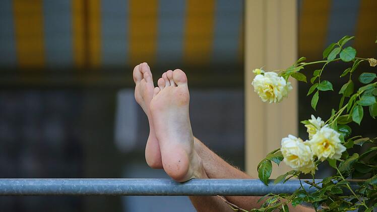 Die F&uuml;&szlig;e eines Mannes sind auf einem Balkon zu sehen