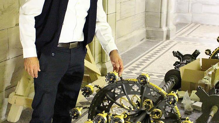 Dekan Roland Huth zeigt die Lüster im neuen, an die Coburger Farben angelehnten, schwarz-goldenen Design. Foto: Ulrike Nauer