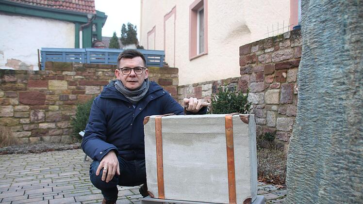 Bürgermeister Armin Warmuth mit dem Koffer aus Metall und Beton, der am Seelhausplatz in der Hammelburger Innenstadt bereits aufgestellt ist. Foto: Ralf Ruppert