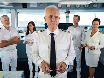 Gerade hat Kreuzfahrt-Direktor Oskar Schifferle (Harald Schmidt, Mitte) Umschl&auml;ge an Kapit&auml;n  Parger (Florian Silbereisen, zweiter von rechts), Hanna Liebhold (Barbara Wussow, rechts), Jessica Delgado (Collien Fernandes) und Martin Grimm (Daniel Morgenroth) verteilt. Darin steht, welchen Aufgaben sich jeder in Auckland stellen soll.