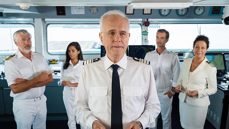 Gerade hat Kreuzfahrt-Direktor Oskar Schifferle (Harald Schmidt, Mitte) Umschläge an Kapitän  Parger (Florian Silbereisen, zweiter von rechts), Hanna Liebhold (Barbara Wussow, rechts), Jessica Delgado (Collien Fernandes) und Martin Grimm (Daniel Morgenroth) verteilt. Darin steht, welchen Aufgaben sich jeder in Auckland stellen soll.