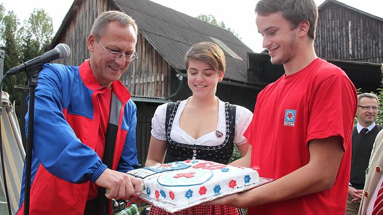 Bereitschaftsleiter Thomas Gremer darf die Geburtstagstorte anschneiden, die Franziska Geyer gebacken hatte und die Corinna und Jannik Wagner überreichten. Foto: Stephan Stöckel