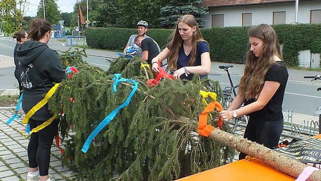 Eine wichtige Aufgabe, bevor der Baum nach oben gehievt wird: das Schm&uuml;cken durch die Kerwasmadli.  Foto: Manfred Welker