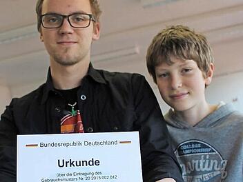 Paul Steinke hält stolz die Urkunde seiner Eintragung des Gebrauchsmusters in den Händen. Rechts daneben der 12-jährige Luca Hohmann. Er und ein weiterer Siebtklässler interessieren sich für "Jugend forscht" und unterstützen Paul Steinke, um einen Einblick zu bekommen.  Foto: Lisa Kieslinger
