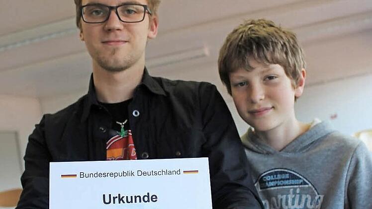 Paul Steinke hält stolz die Urkunde seiner Eintragung des Gebrauchsmusters in den Händen. Rechts daneben der 12-jährige Luca Hohmann. Er und ein weiterer Siebtklässler interessieren sich für "Jugend forscht" und unterstützen Paul Steinke, um einen Einblick zu bekommen.  Foto: Lisa Kieslinger