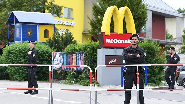 Polizeibeamte stehen am 23.07.2016 vor dem McDonald's Schnellrestaurant am Olympia-Einkaufszentrum OEZ in München, einen Tag nach einer Schießerei mit Toten und Verletzten. Foto: Sven Hoppe/dpa