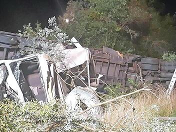 Nachdem der Sattelzug und der Kleintransporter die Leitplanke durchbrochen und eine Böschung hinuntergestürzt waren, blieben die verunglückten Fahrzeuge auf der Seite liegen.