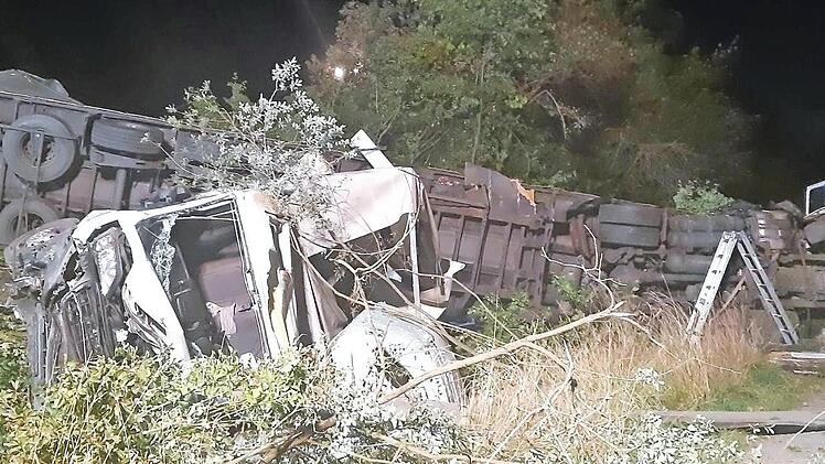 Nachdem der Sattelzug und der Kleintransporter die Leitplanke durchbrochen und eine Böschung hinuntergestürzt waren, blieben die verunglückten Fahrzeuge auf der Seite liegen.