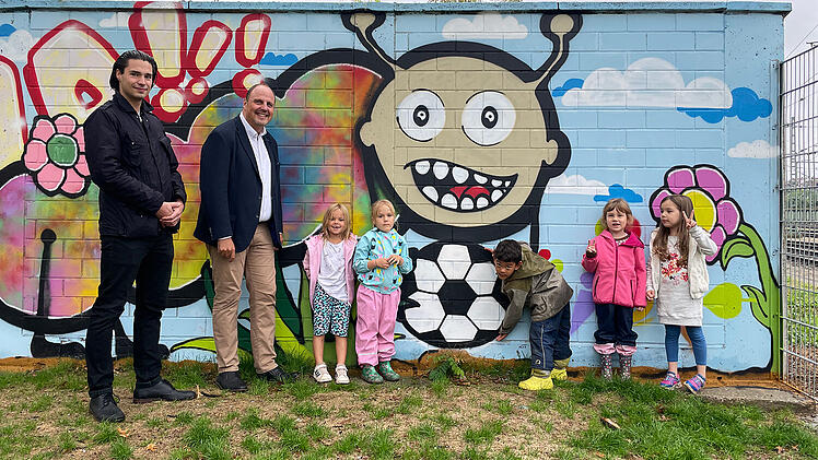 N&uuml;rnberg: Kinder versch&ouml;nern mit Graffitik&uuml;nstler Betonwand am Bolzplatz Austra&szlig;e - auch historische Sandsteinmauer wurde saniert