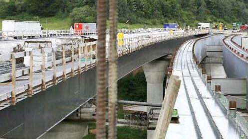 Alt und neu: Rechts ist der Stahl-Doppelstrang zu erkennen, der die Fahrbahn trägt, links folgt die Gegen-Richtung mit bereits betonierter Fahrbahndecke, dahinter rollt der Verkehr auf der alten Brücke.