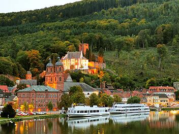 Blick vom Main auf die hell erleuchtete Festung Mildenburg in Miltenberg am Main in der Abenddämmerung  an einem schönen Herbsttag