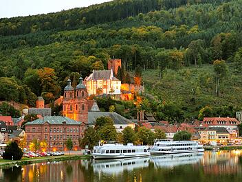 Blick vom Main auf die hell erleuchtete Festung Mildenburg in Miltenberg am Main in der Abendd&auml;mmerung  an einem sch&ouml;nen Herbsttag