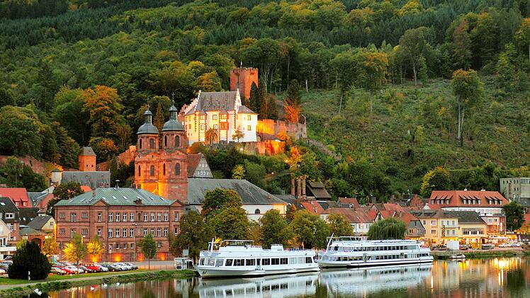 Blick vom Main auf die hell erleuchtete Festung Mildenburg in Miltenberg am Main in der Abenddämmerung  an einem schönen Herbsttag