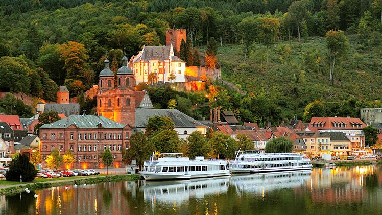 Blick vom Main auf die hell erleuchtete Festung Mildenburg in Miltenberg am Main in der Abendd&auml;mmerung  an einem sch&ouml;nen Herbsttag