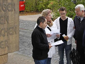 Atilla Karabag, Marita Obermeyer-Simsekly, Patrick Schroll sowie der Lokalhistoriker Rolf Kiessling und FW-Stadtrat Ludwig Preusch (von links) diskutieren zwischen dem Gedenkstein und dem  als Parkplatz genutzten ehemaligen Synagogengrundstück (im Hintergrund). Foto: Andreas Oswald