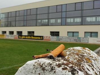 Wohin mit den Rauchern bei Großveranstaltungen in der Sander Turnhalle? Hier unten am Fußballplatz ist das auch so eine Sache, denn das wertvolle Rasenspielfeld sollte nicht beschädigt werden. Doch oben auf dem Parkplatz vis a vis der Anlieger stören die bis zu 100 Mann, die bei einem Event mal schnell Luft schnappen und eine rauchen wollen. Durch die Türen dringt der Lärm nach draußen, und auch sonst bringt das Getriebe Unruhe in die ruhige Wohngegend. Der Gemeinderat wird in Sachen Turnhall...