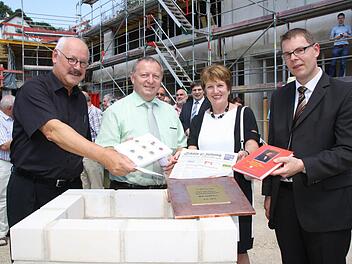 Architekt Dieter Ben Kaufmann (von links) legte eine CD mit Plänen, Landrat Thomas Bold eine Münzsammlung, Bürgermeisterin Brigitte Meyerdierks die Saale-Zeitung und Stiftungsvorstand Marco Schäfer ein Buch über den Stifter Carl von Heß in eine Schatulle, die in der Grundplatte versenkt wird. Fotos: Ralf Ruppert