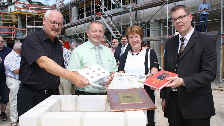 Architekt Dieter Ben Kaufmann (von links) legte eine CD mit Plänen, Landrat Thomas Bold eine Münzsammlung, Bürgermeisterin Brigitte Meyerdierks die Saale-Zeitung und Stiftungsvorstand Marco Schäfer ein Buch über den Stifter Carl von Heß in eine Schatulle, die in der Grundplatte versenkt wird. Fotos: Ralf Ruppert