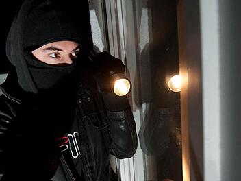 Auf diesem gestellten Bild versucht ein Einbrecher, durch ein Fenster in eine Wohnung einzudringen. Foto: Andreas Gebert, dpa